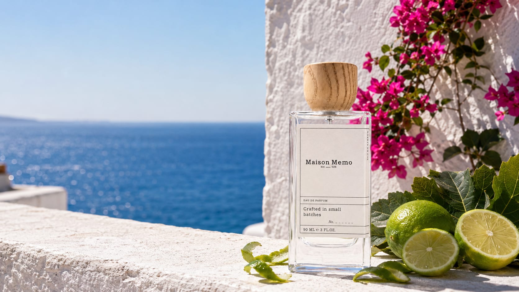The flacon on a whitewashed stone ledge above a bright blue sea, bougainvillea and split limes at its base in hard afternoon sun.