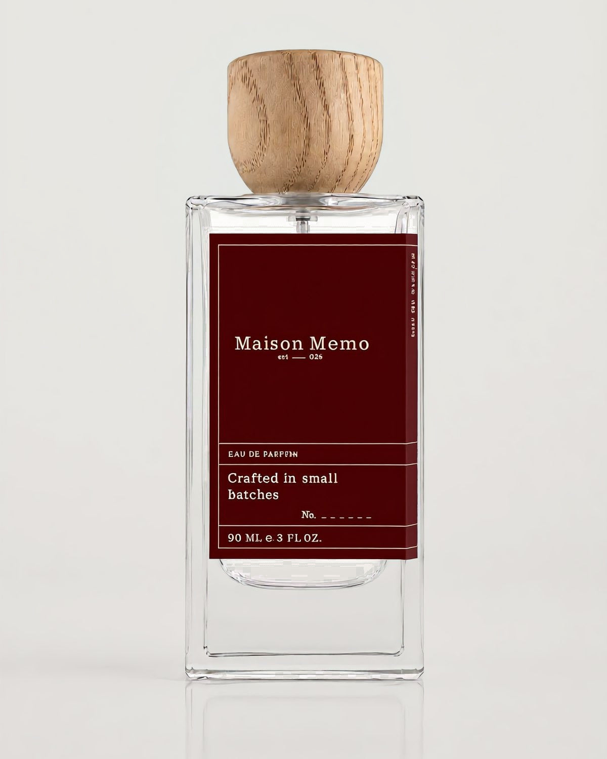 The 90 ml flacon square-on against white seamless, burgundy letterpress label under a turned oak cap.
