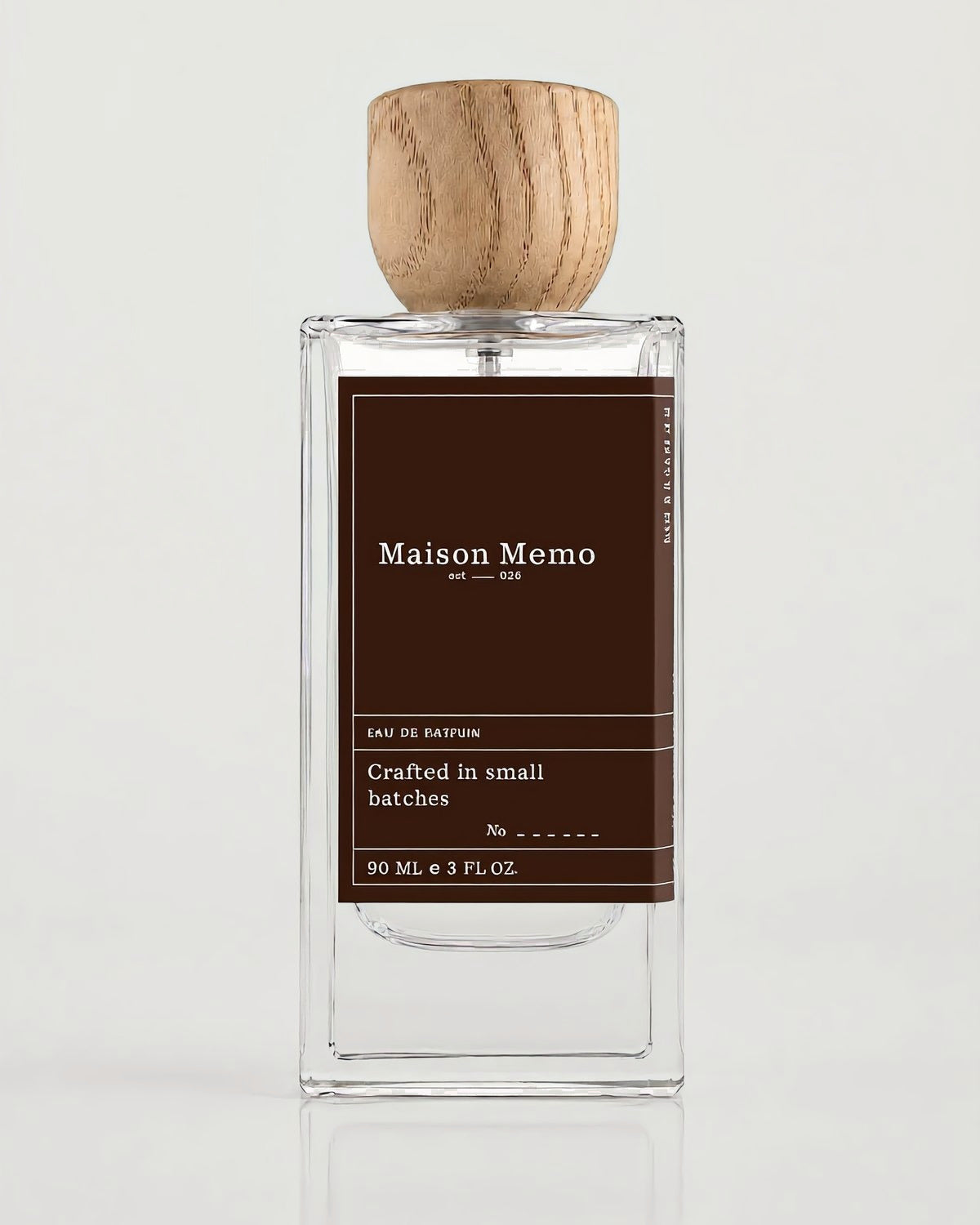 The 90 ml flacon square-on against white seamless, near-black charcoal letterpress label under a turned oak cap.