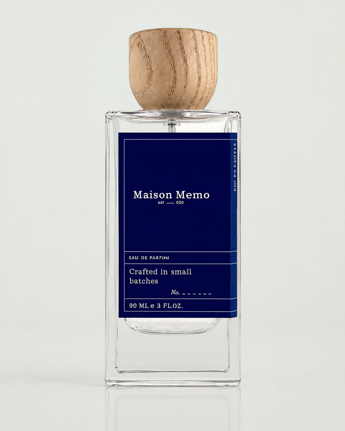 The 90 ml flacon square-on against white seamless, indigo letterpress label under a turned oak cap.